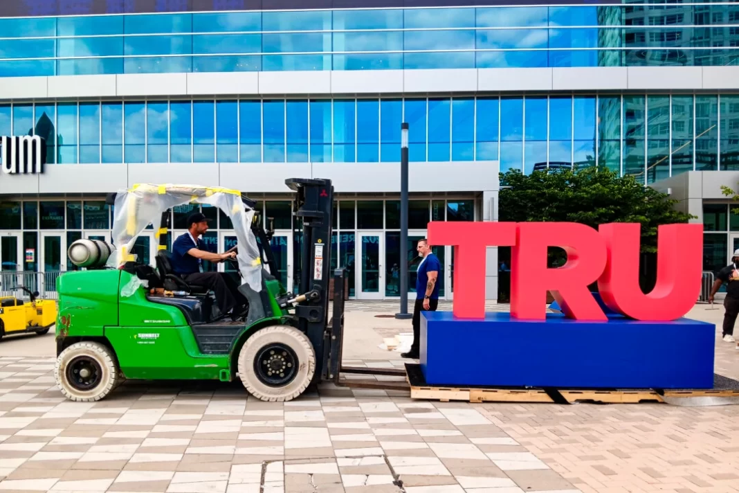 Workers disassemble the words "TRUMP 2024" outside the Fiserv Forum