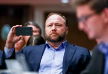 InfoWars founder Alex Jones takes photos at a hearing