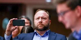 InfoWars founder Alex Jones takes photos at a hearing