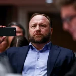 InfoWars founder Alex Jones takes photos at a hearing