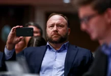 InfoWars founder Alex Jones takes photos at a hearing